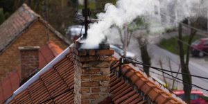 Chimney with smoke coming out of it. Chimney Cleaning by Masonry Waterproofing, and Drainage Masters serving Portland OR and Vancouver WA