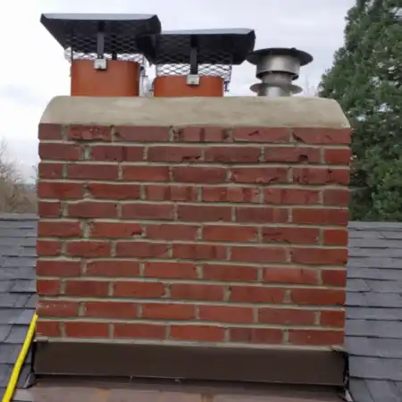 chimney-after-shot A newly repaired residential brick chimney equipped with fresh mortar, new flashing, and metal spark-arrestor chimney caps.