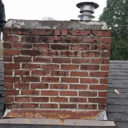 chimney-before-shot An aging brick chimney with weathered masonry and rusted metal flashing prior to restoration.