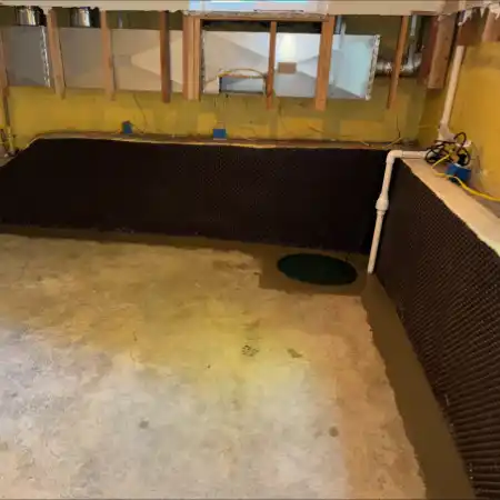 interior-basement-corner A completed basement waterproofing system featuring wall drainage panels, and an integrated sump basin.
